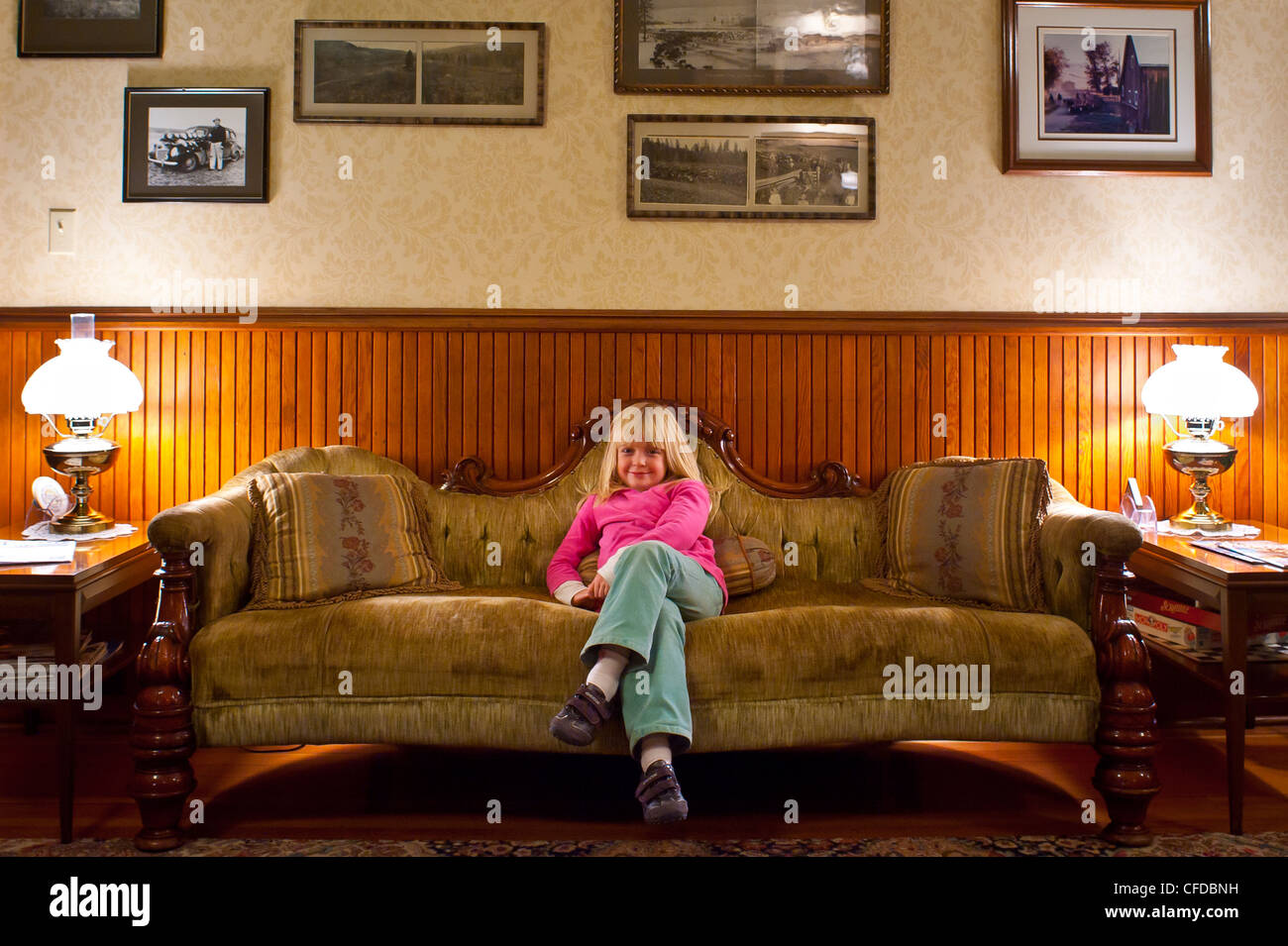 Bambina di cinque anni sul divano di antiquariato. Hotel Quilchena, British Columbia, Canada. Foto Stock