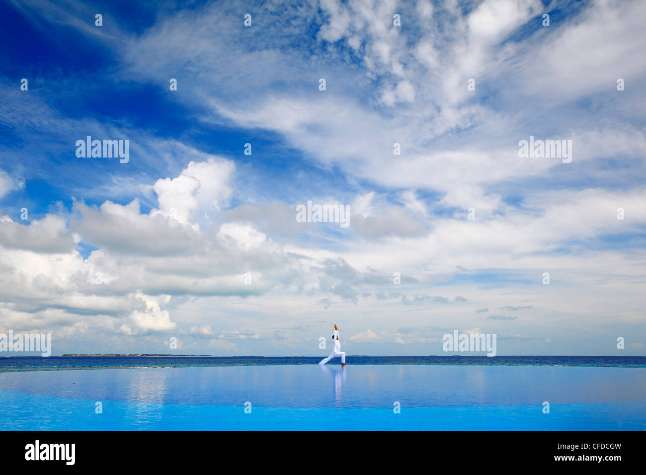 Giovane uomo meditando da piscina infinity, Maldive, Oceano Indiano, Asia Foto Stock