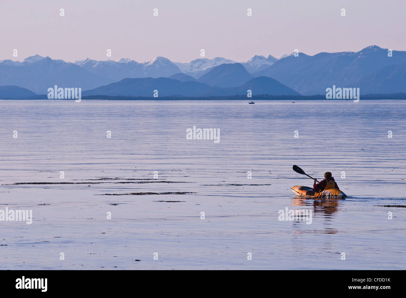 Un kayaker al tramonto con la westcoast mountain range in background, Merville, British Columbia, Canada Foto Stock