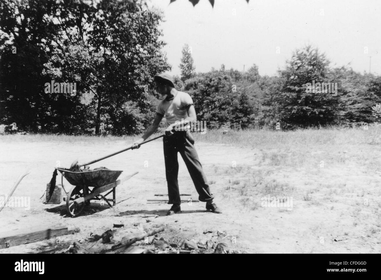 Ragazzo mettendo le rocce in ruota vintage barrow durante gli anni quaranta anni trenta midwest America il lavoro manuale ragazzo adolescente uomo Foto Stock