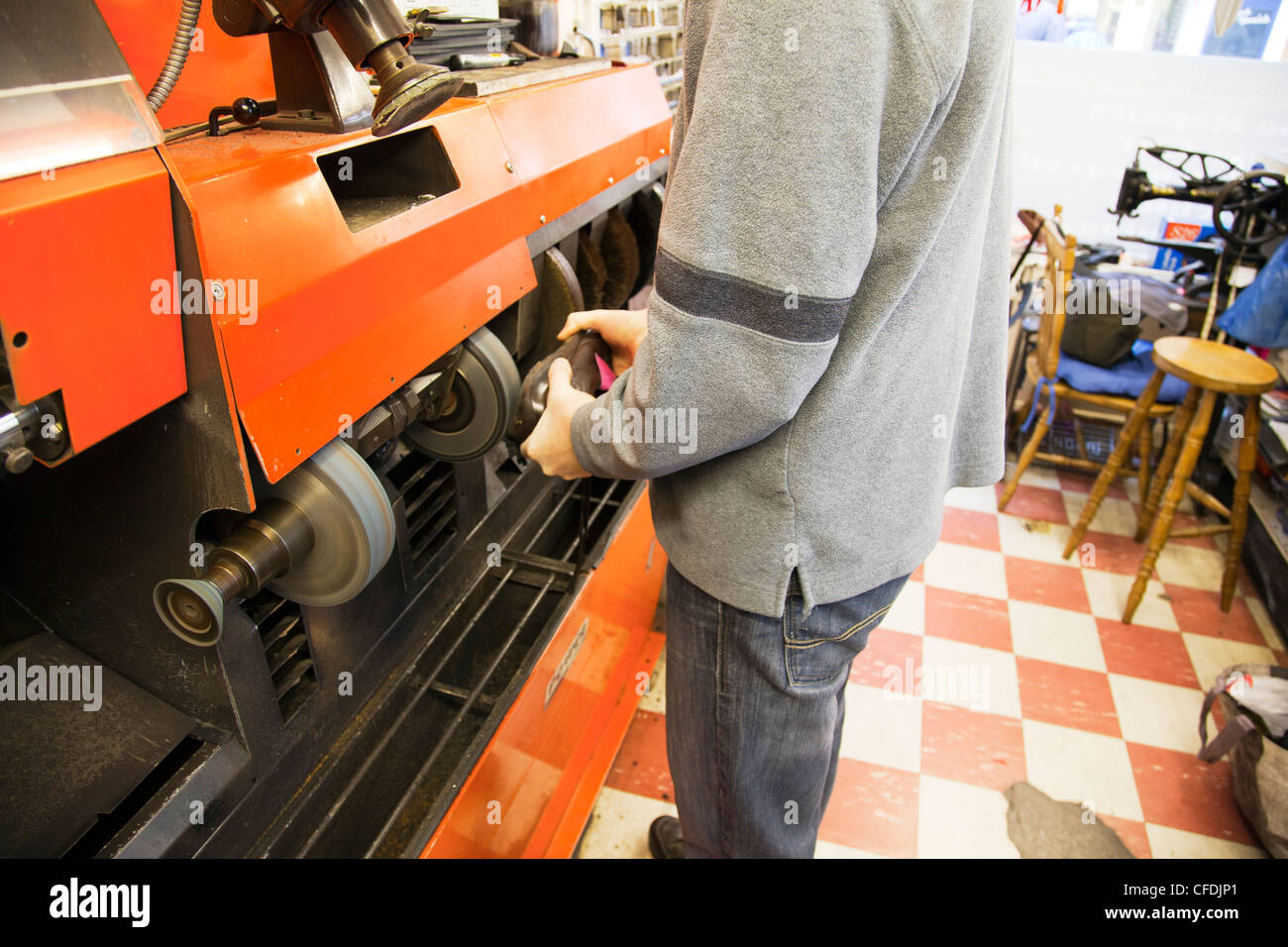 Calzolaio rammendo scarpe in cobblers shop lavorando sulla macchina per smerigliare e lucidare le scarpe Foto Stock