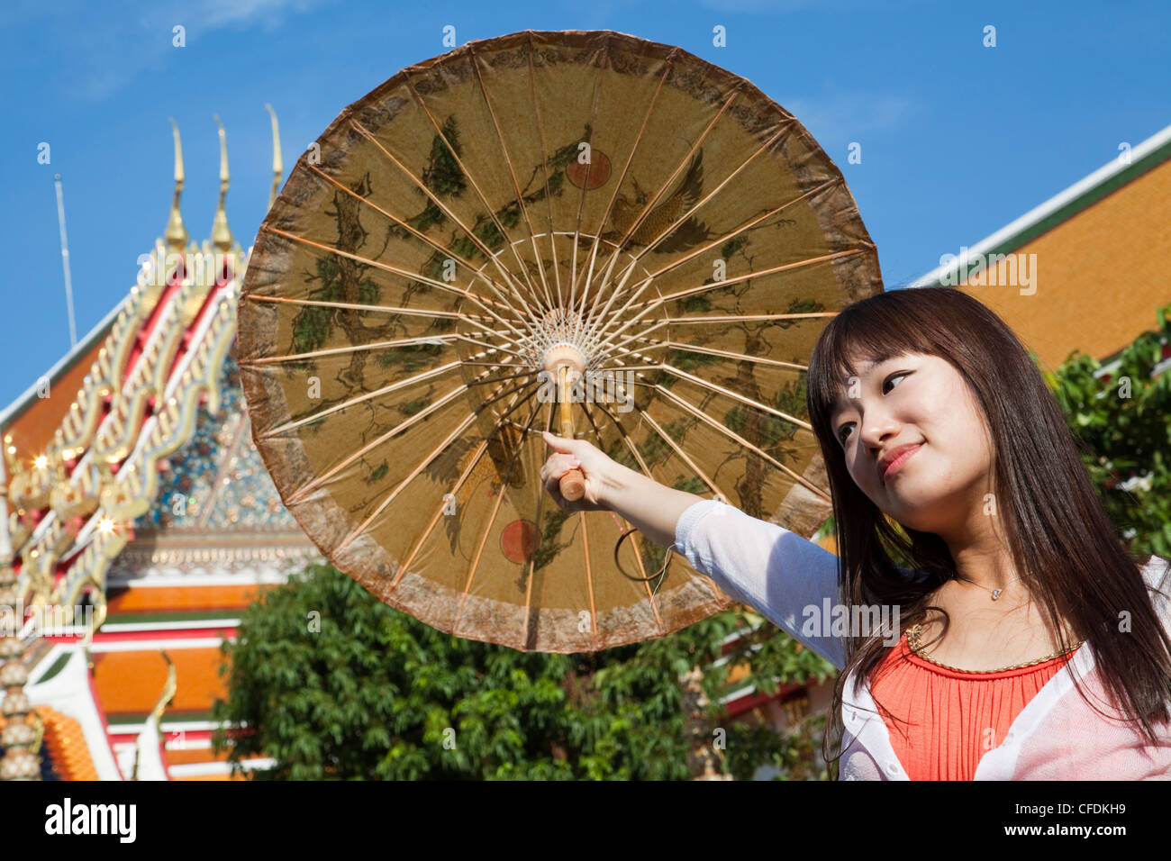 Donna asiatica con ombrellone al Wat Pho, il Tempio del Buddha Reclinato, Bangkok, Thailandia Foto Stock