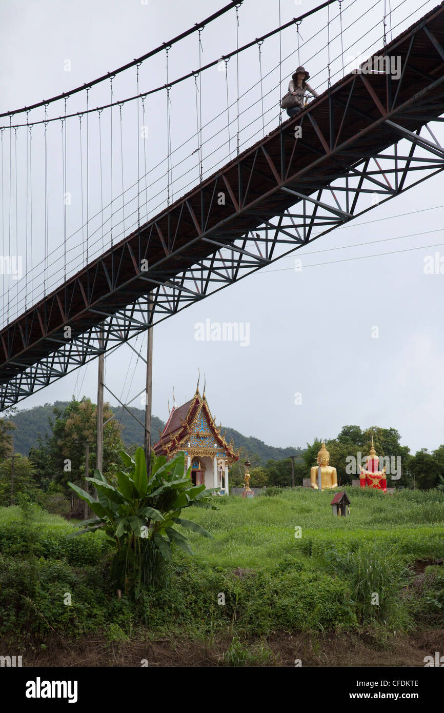 Cicli di donna attraverso Ponte sul Fiume Kwai Noi vicino Sai Yok National Park, vicino a Kanchanaburi Thailandia Foto Stock