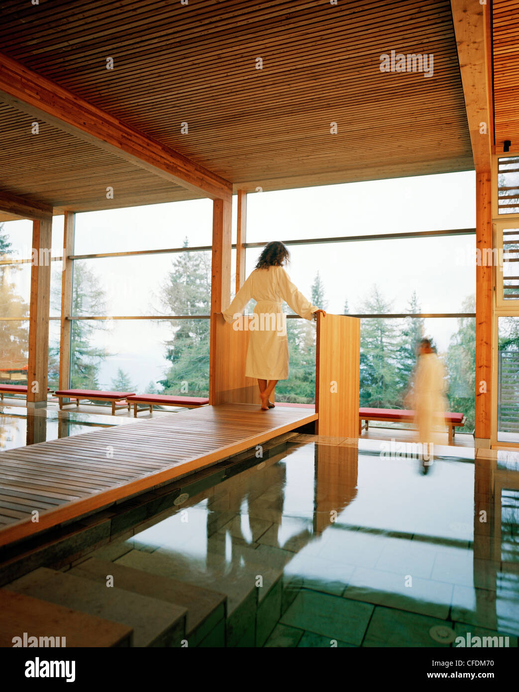 Giovane vicino alla piscina coperta guardando fuori della finestra panoramica, Vigilius Mountain Resort, S. Vigilio, Lana, Trentino-Alto Adige/Suedtir Foto Stock