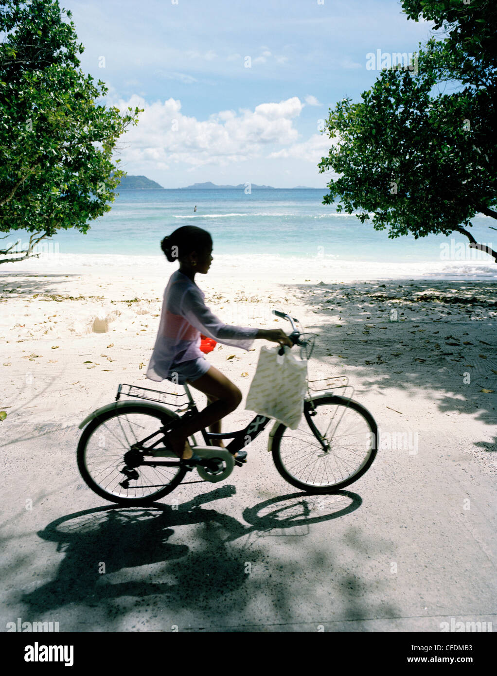 Ciclista ad Anse Severe Beach, a nord-ovest di La Digue, La Digue e isole interne, Repubblica delle Seicelle, Oceano Indiano Foto Stock