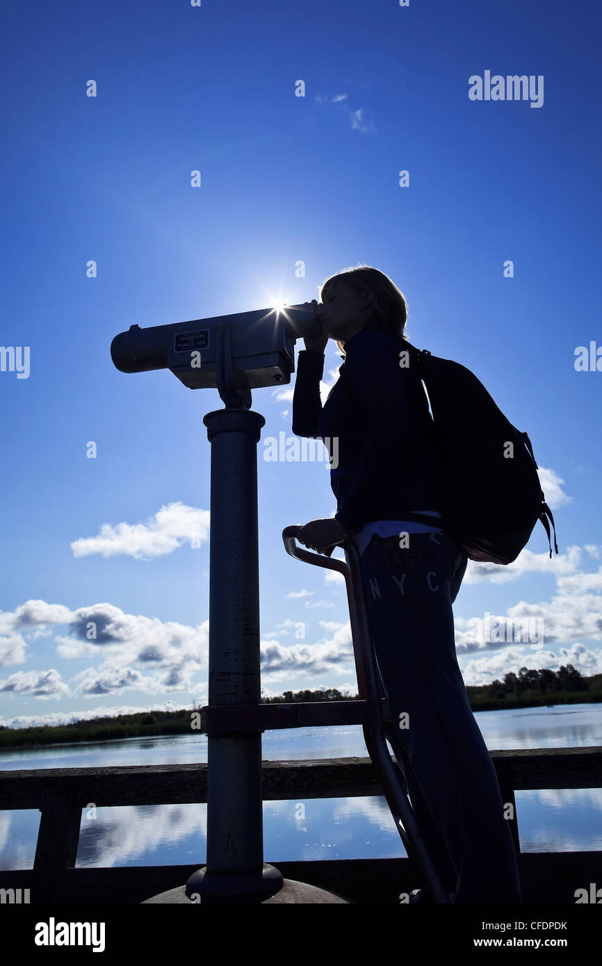 Donna che guarda attraverso un telescopio, bird watching, erboso si restringe Marsh, Hecla Isola Parco Provinciale, Manitoba, Canada. Foto Stock