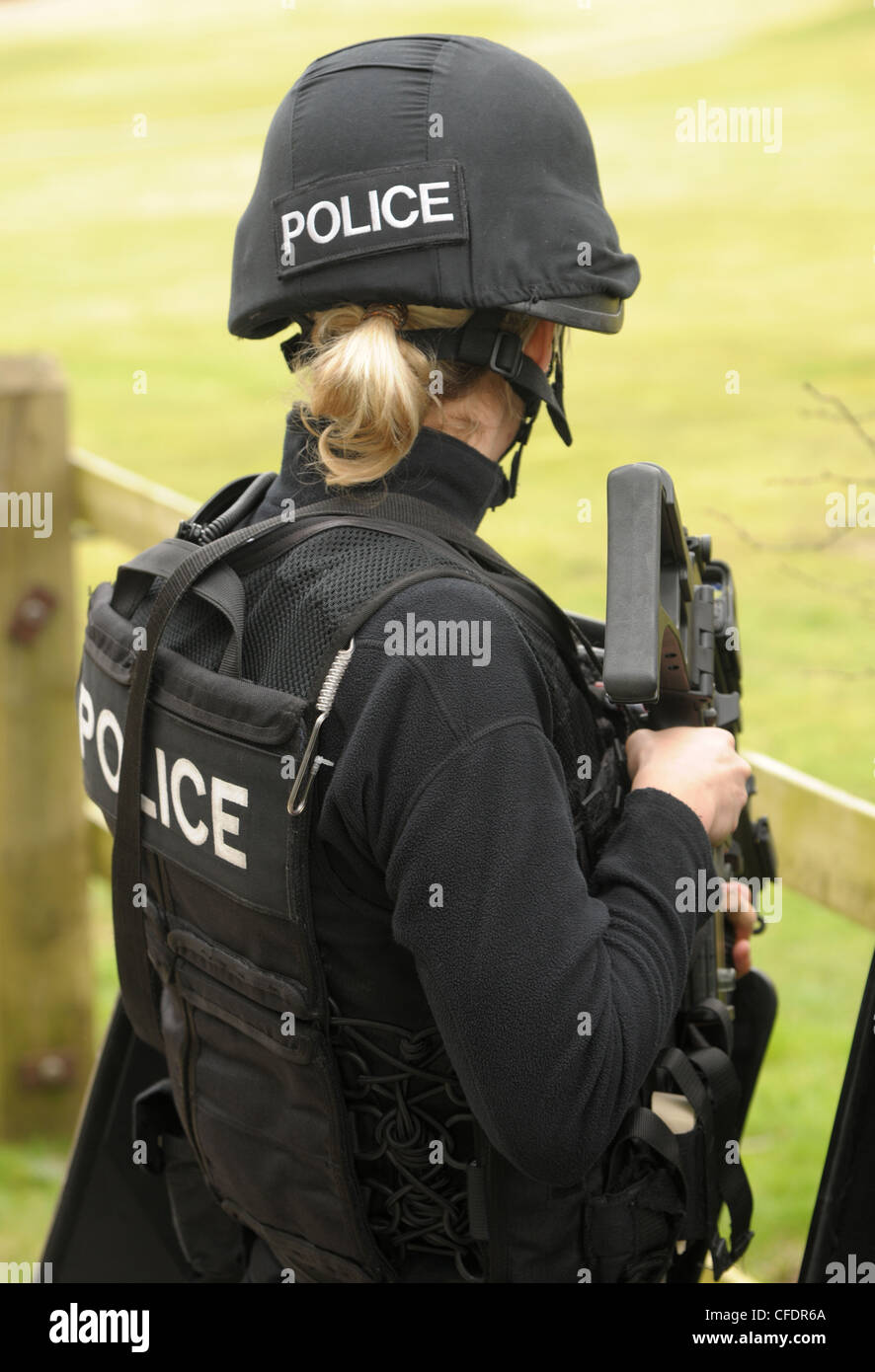 Una femmina di polizia ufficiale di armi da fuoco armati con un Heckler e Koch G36C fucile da assalto osserva un incidente. La polizia reale SWAT. Foto Stock