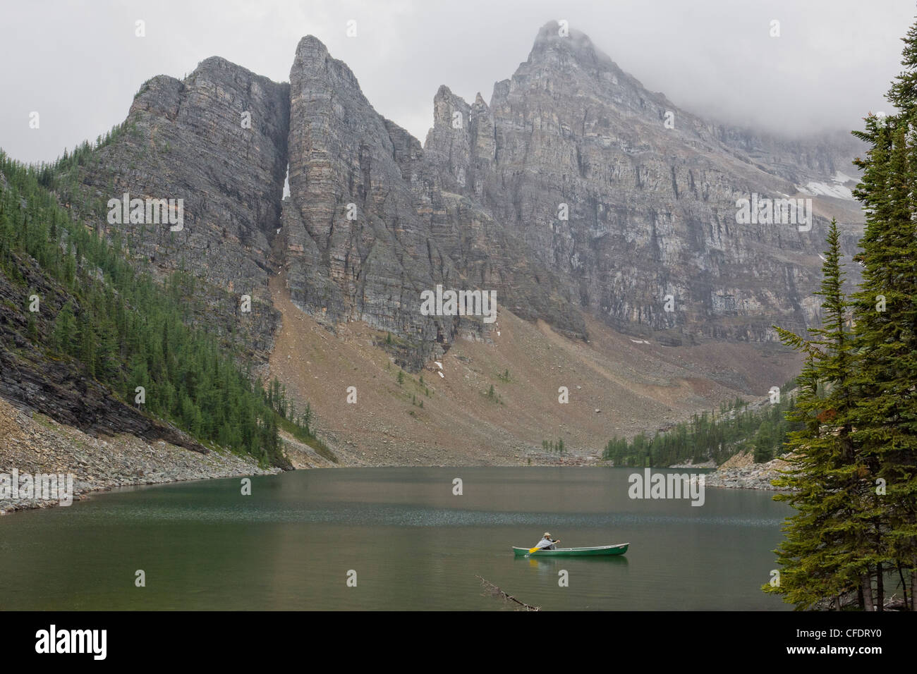 Uomo in canoa sul Lago di Agnese in una piovosa giornata nel Parco Nazionale di Banff, Alberta, Canada Foto Stock