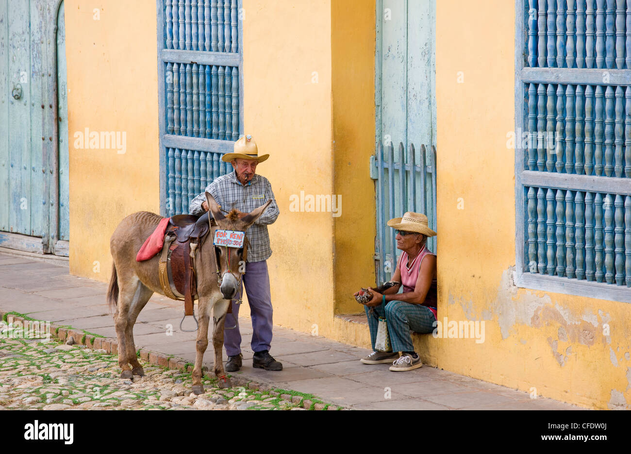Uomo locale con il suo asino e un altro con il suo galletto, Galaria de arts, Trinidad, Cuba, West Indies Foto Stock