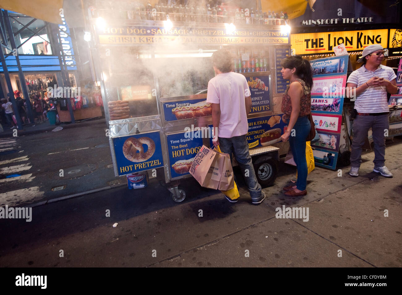 Giovane acquisto di hot dogs in Times Square a New York, di notte. Stati Uniti d'America. Foto Stock