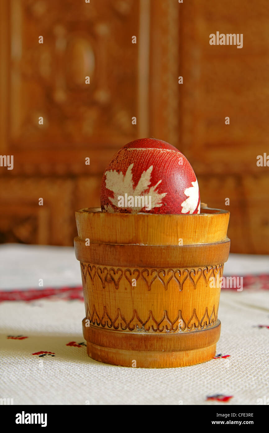 Dipinto di uovo di Pasqua in un tradizionale contenitore di legno con la riflessione della luce. Foto Stock