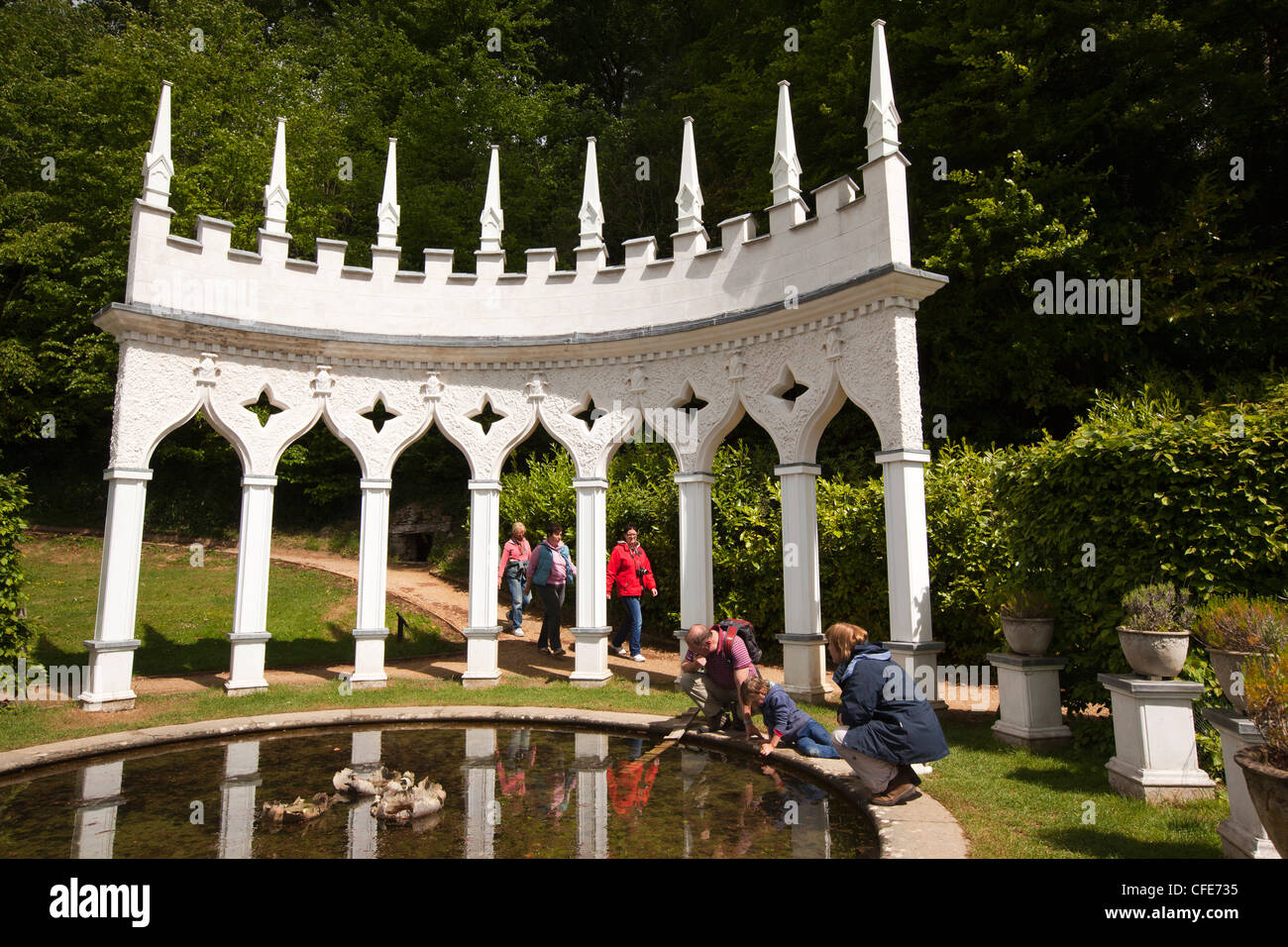 Regno Unito, Gloucestershire, Painswick House, Rococò giardino, stagno sul dipinto di bianco exedra area con posti a sedere Foto Stock