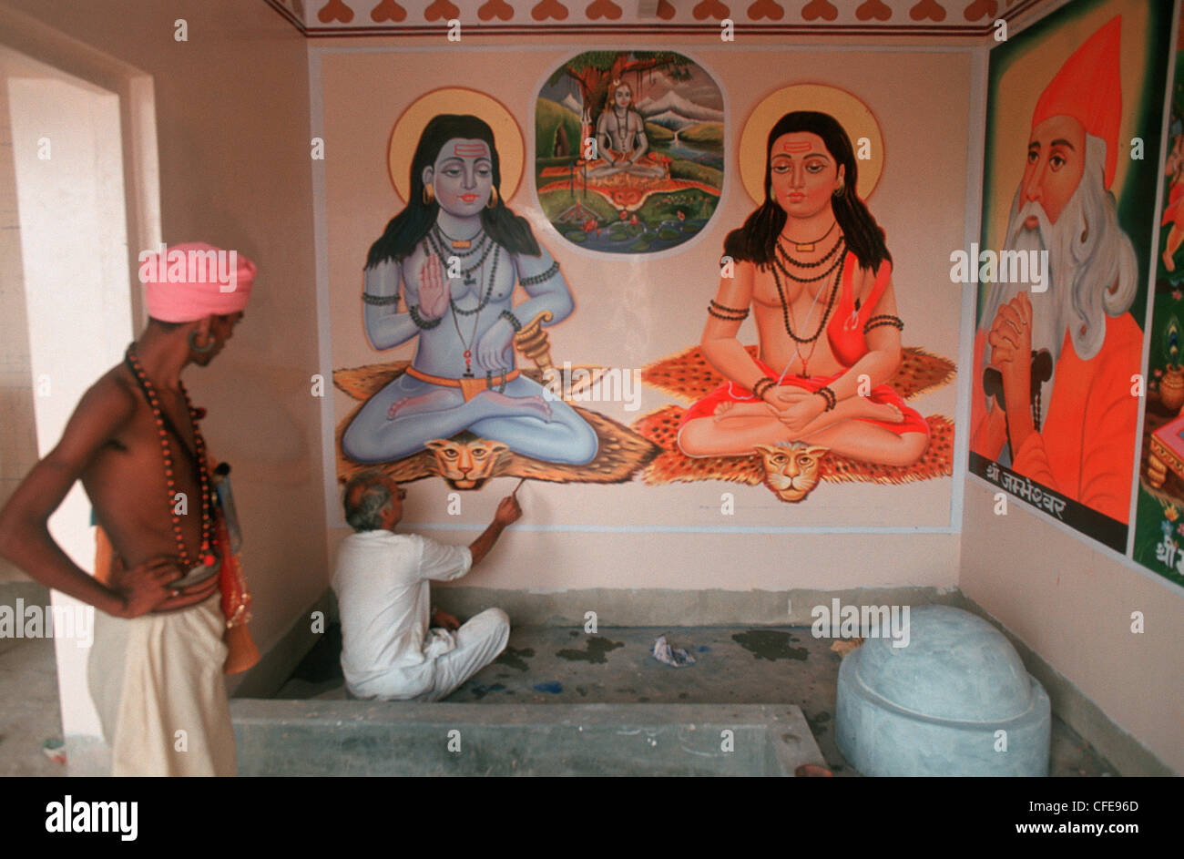 In un tempio, un artista è la pittura divinità Indù in posture yoga. Sulla sinistra, un asceta indù ('sadhu') è guardare ( India) Foto Stock