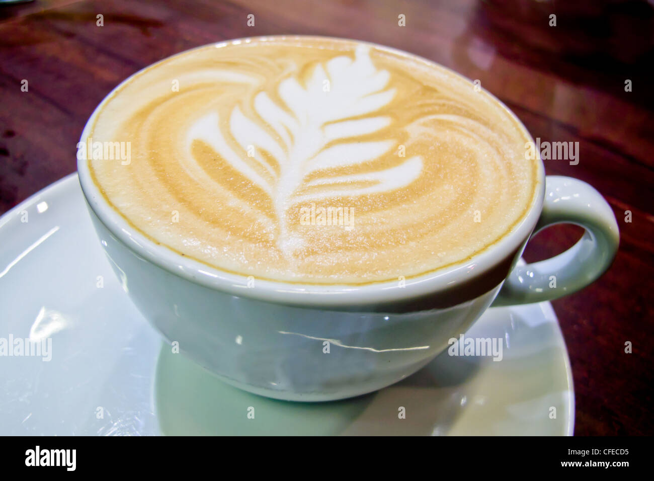 Piatto bianco caffè con una foglia modello sulla parte superiore Foto Stock
