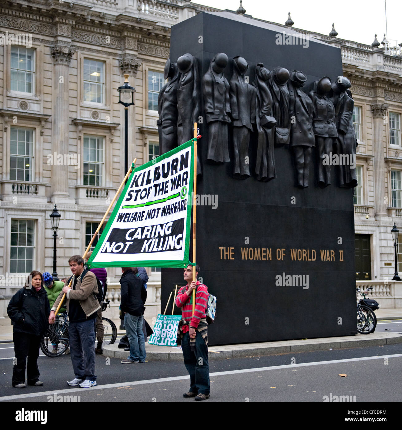 Anti-guerra di manifestanti tenendo un banner al Monumento Nazionale per le donne della II Guerra Mondiale, London REGNO UNITO Foto Stock