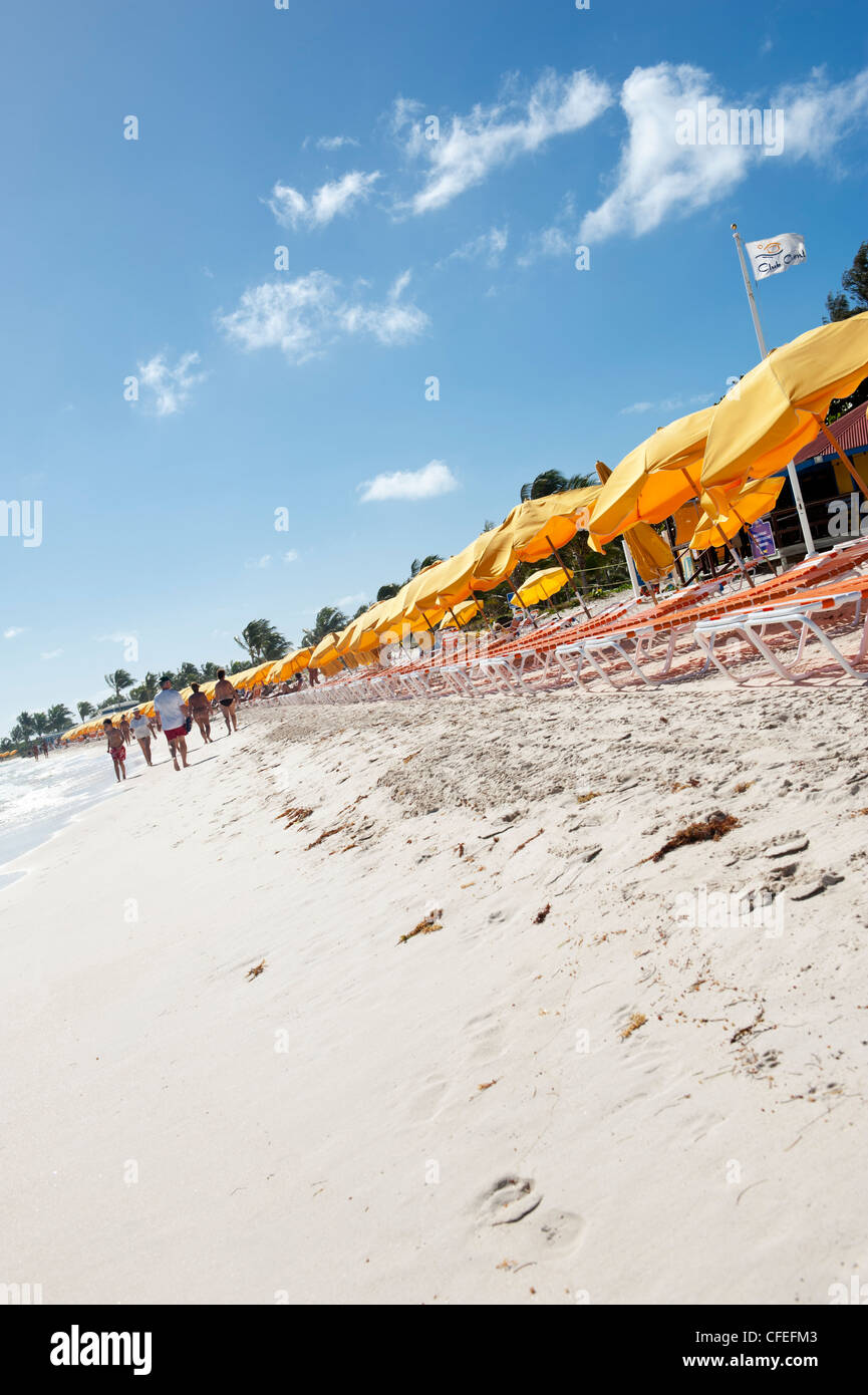 La gente camminare lungo la riva di Orient Beach Saint Martin, con ombrelli gialli Foto Stock