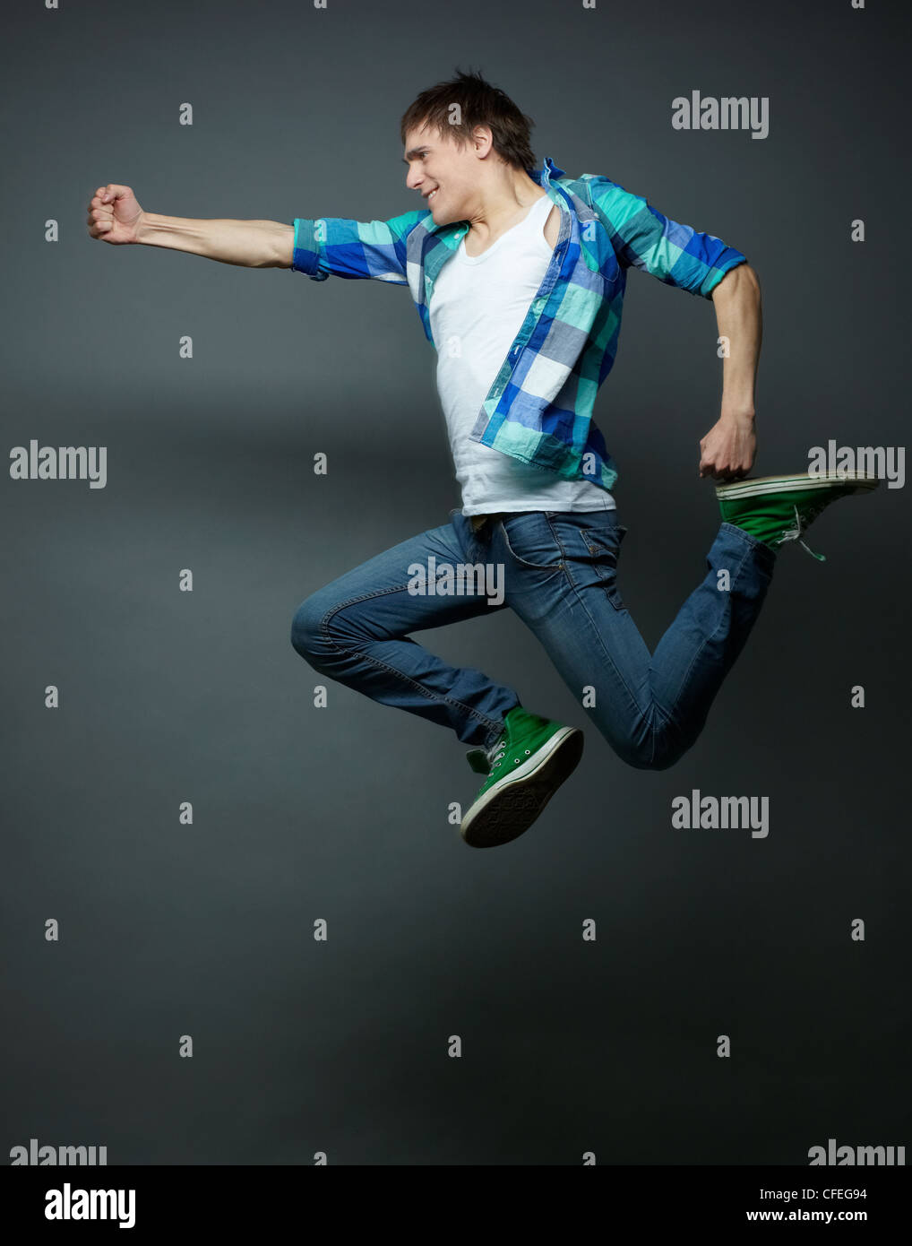 Energetic guy jumping con i pugni serrati stretto e calci l'aria Foto Stock