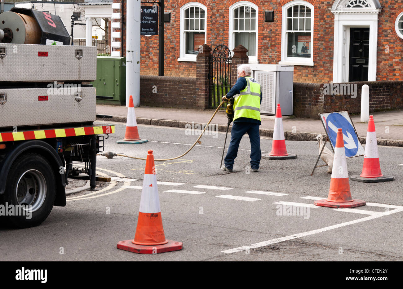 L'uomo circa per scavare fino alla strada roadworks Beaconsfield città nuova Bucks REGNO UNITO Foto Stock