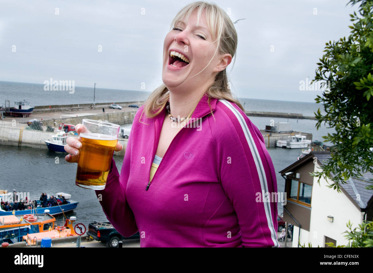 Venti qualcosa di ragazza che si gode di bere una pinta di birra lager Foto Stock