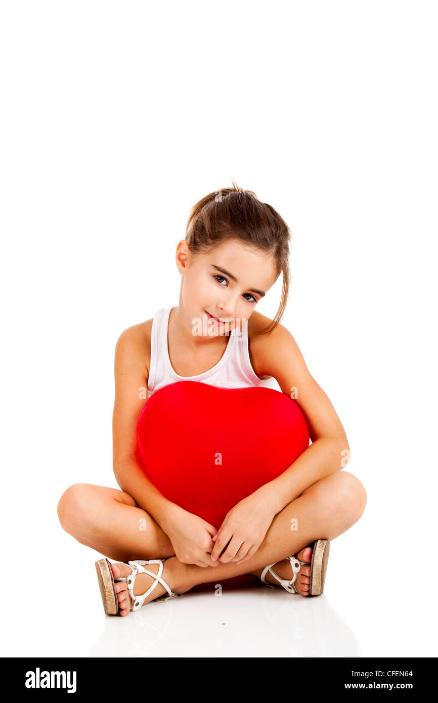 Ritratto di una bambina seduta sul pavimento e abbracciando un palloncino rosso, isolato su sfondo bianco Foto Stock