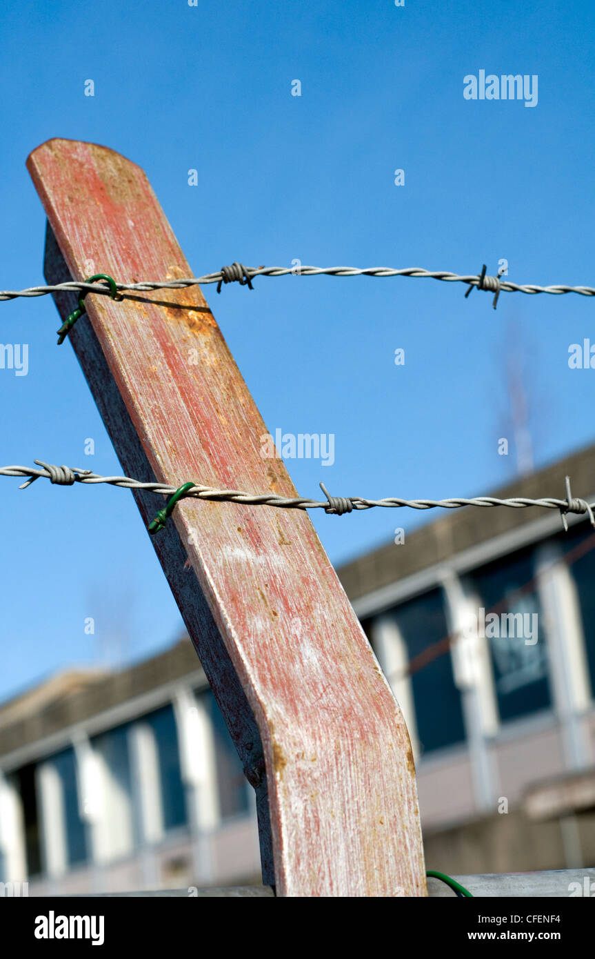 Una sezione di filo spinato di fronte ad un edificio abbandonato Foto Stock