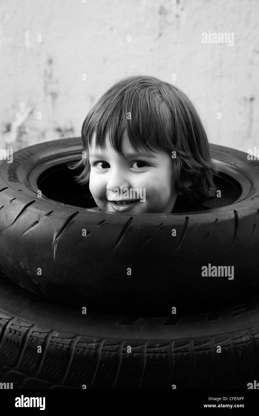 Tre anni di vecchio ragazzo giocando nella pila di gomme. Foto Stock