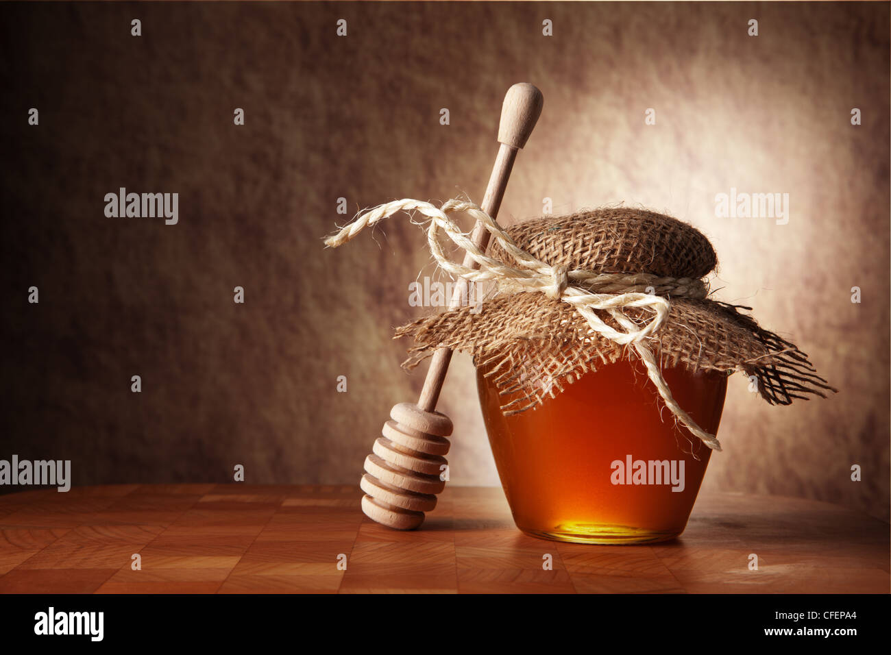 Vasetto di miele e di bastone di legno sono su un tavolo. Foto Stock