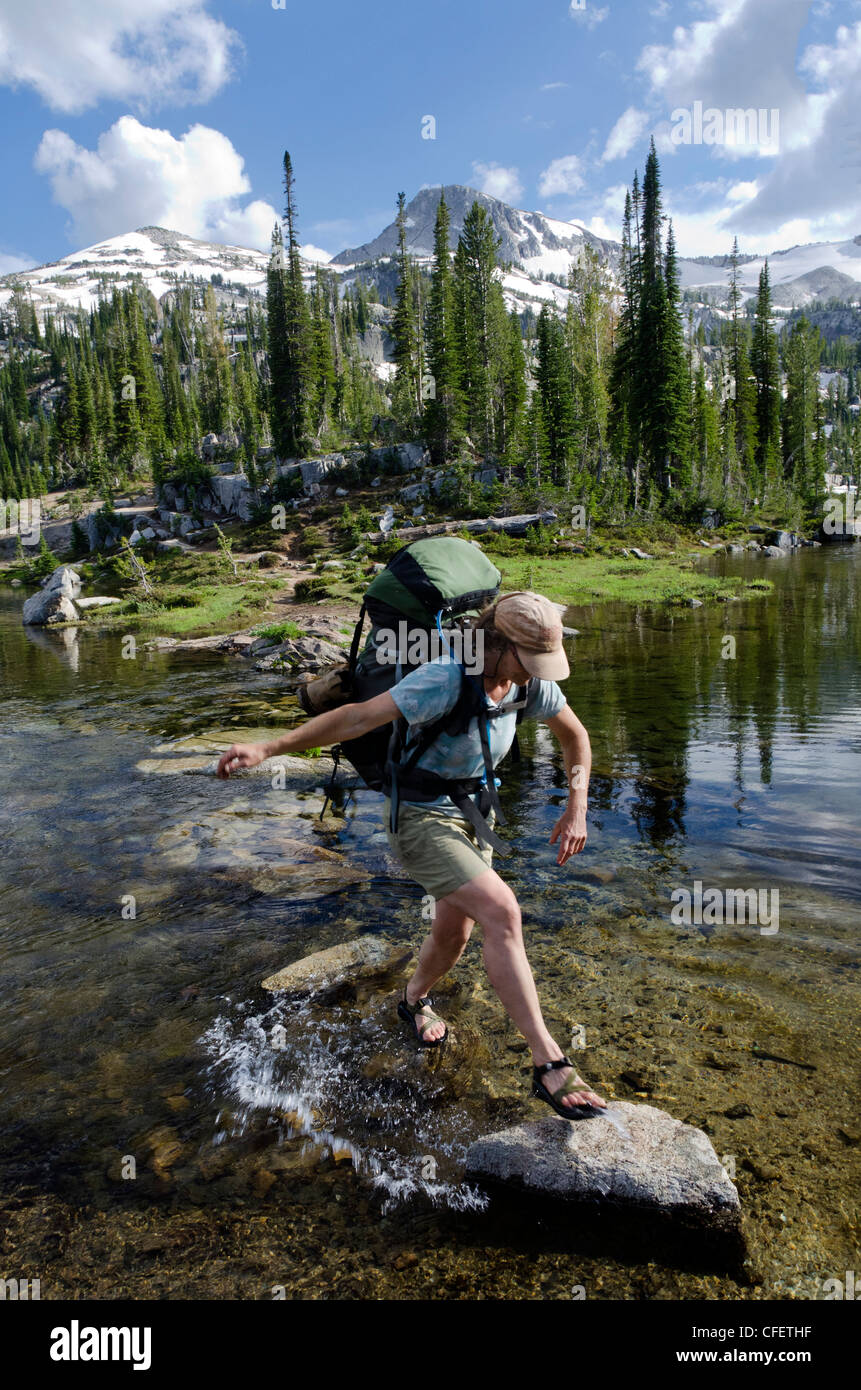 Backpacker incrocio su pietre, Mocassino Lago, Wallowa Mountains, Oregon. Foto Stock