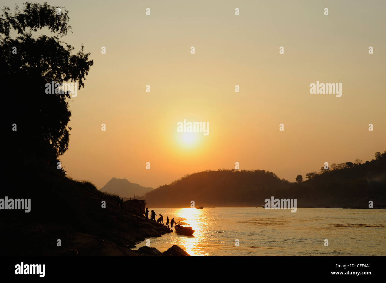 Tramonto sul Mekong, persone lasciando piccole traghetto, imbarcazioni presso le rive del fiume Mekong a Luang Prabang, Laos Foto Stock