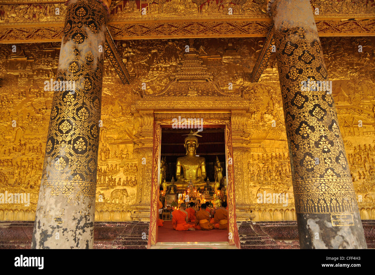 Galleria con golden sollievo e monaci in preghiera della sera, Wat Mai Suwannaphumaham, Luang Prabang, Laos, democratica del Laos Rep Foto Stock