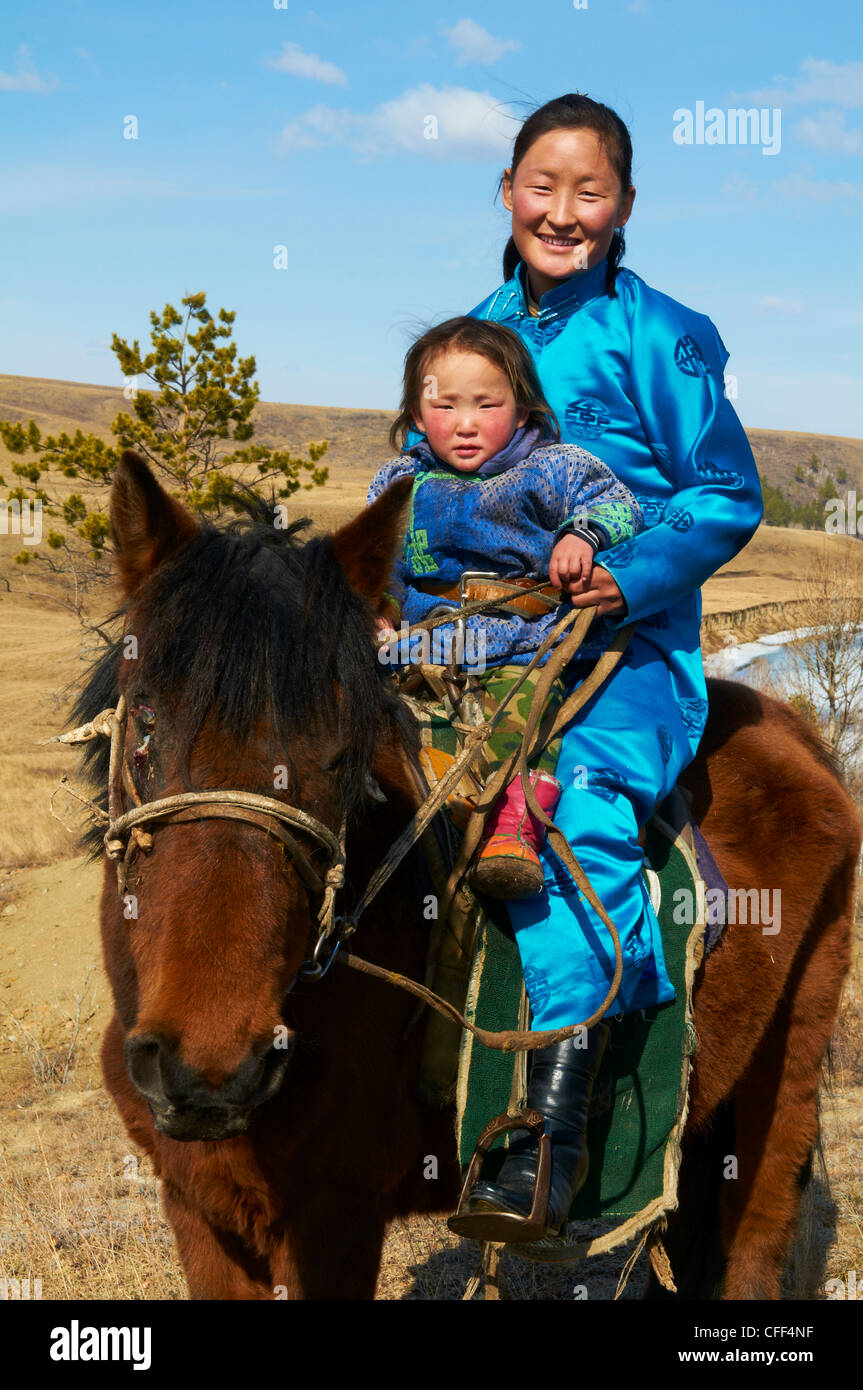 Mongolo giovane donna e bambino in costume tradizionale (deel) in sella ad un cavallo, Provincia di Khovd, Mongolia, Asia Centrale, Asia Foto Stock