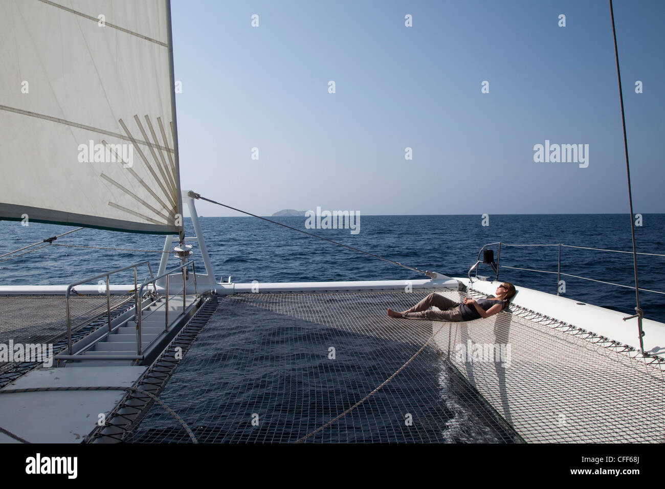 La donna si rilassa su net di catamarano SY Azzura, Ocean Blue Oman crociere, durante escursioni in barca a vela, Muscat, Masqat, Oman, Arabian Pe Foto Stock