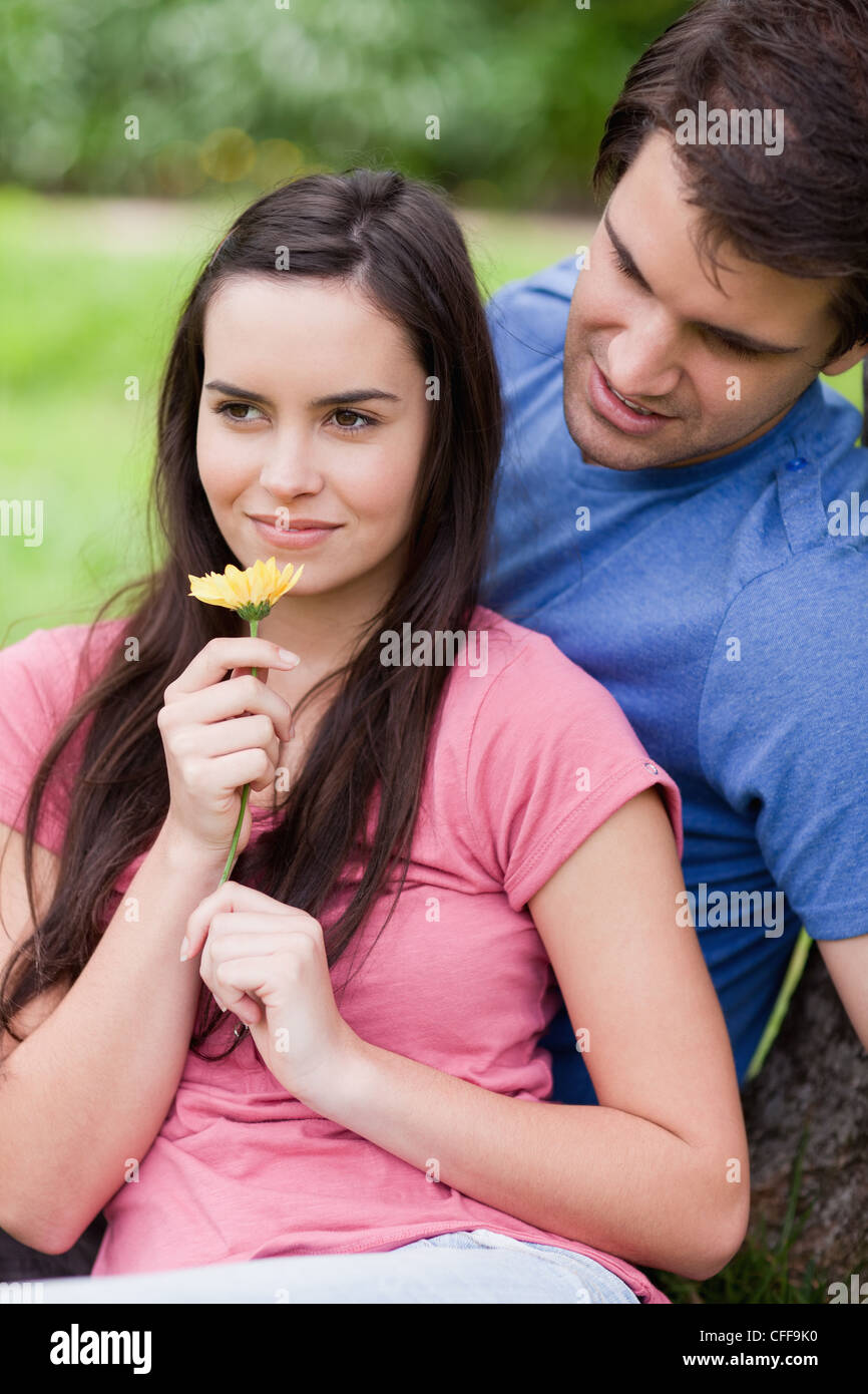 Giovane donna odorare un fiore mentre viene accompagnata dal suo fidanzato Foto Stock