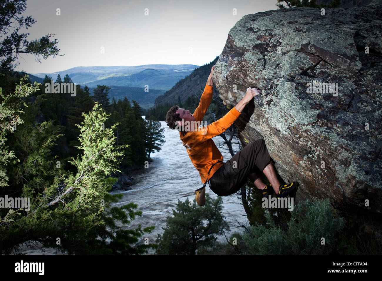 Un uomo atletico bouldering al di sopra di un fiume in Montana. Foto Stock