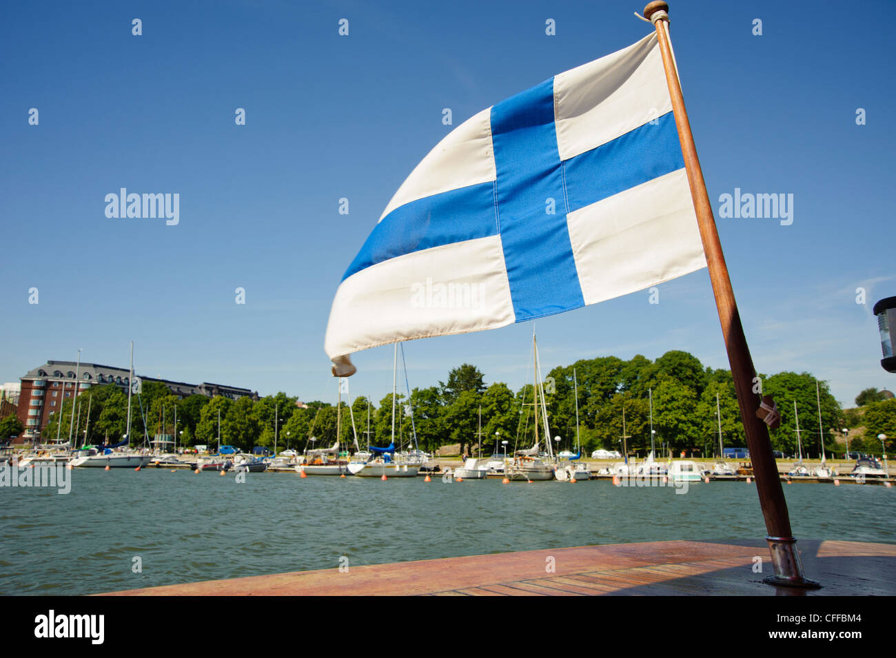 La bandiera finlandese vola da una barca manovre di inversione tra Unisaari island e il Merisatama quayside, Helsinki Finlandia Foto Stock
