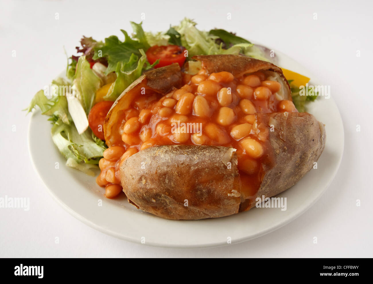 Un fagioli cotti al forno di patate al forno su una piastra con insalata di contorno Foto Stock