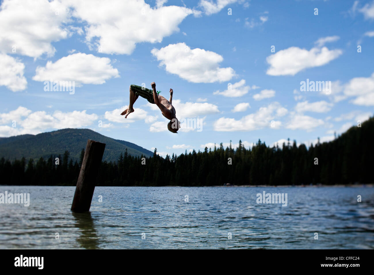 Un giovane uomo backflipping off di un molo presso un lago in Idaho. Foto Stock