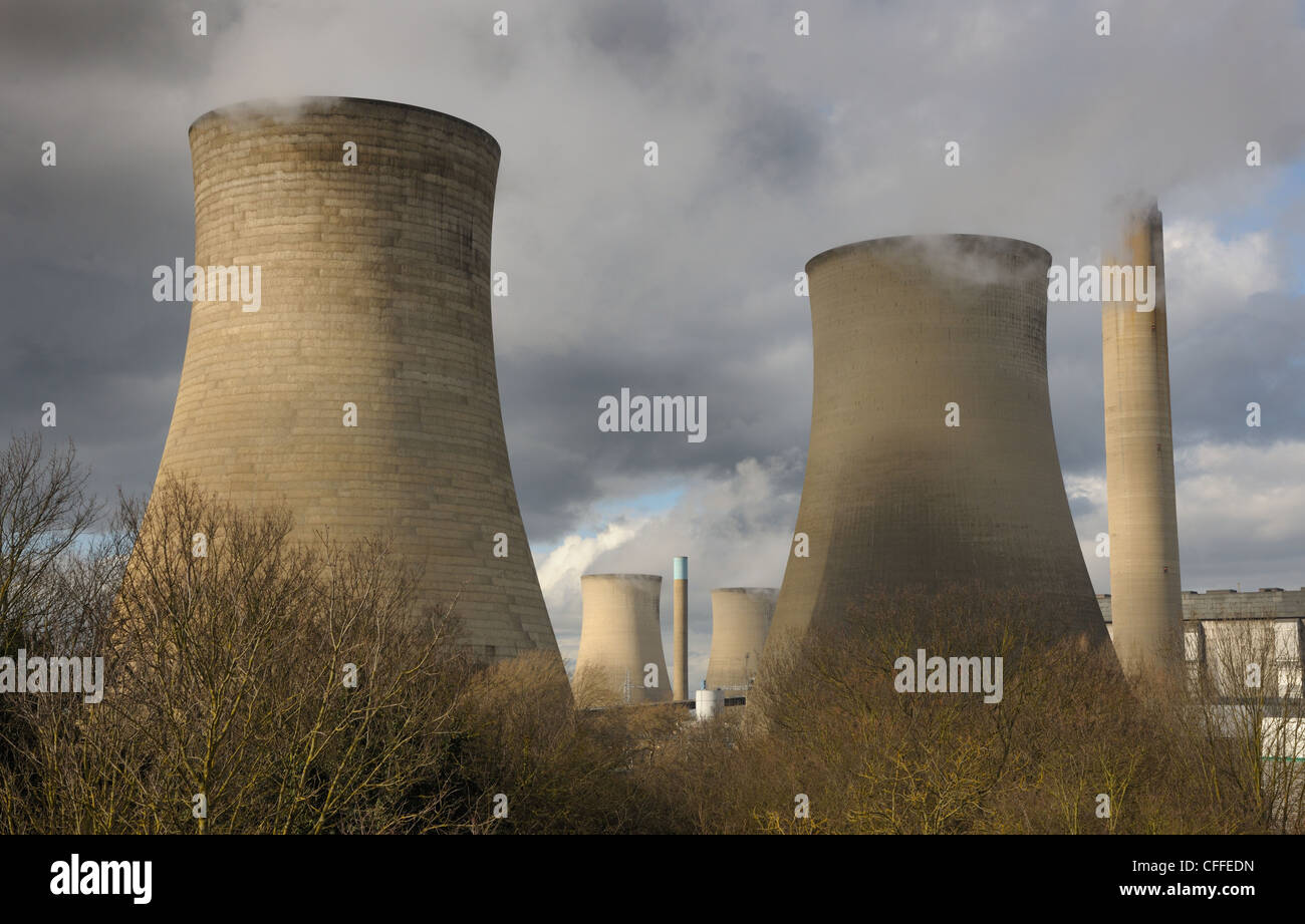 Gigante di torri di raffreddamento alla generazione di elettricità stazione. Bianco vapore contro un moody sky con sole invernale. Foto Stock