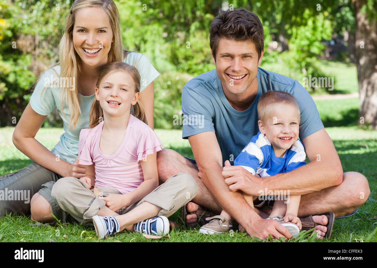 Famiglia sorridente seduto sull'erba azienda uno un altro Foto Stock