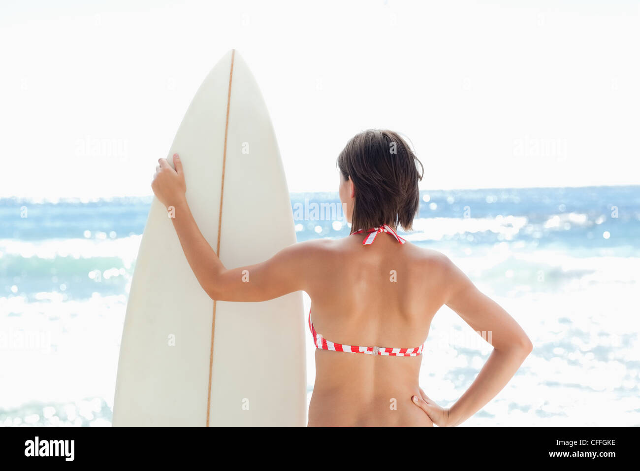 Donna che mantiene una tavola da surf guardando a sinistra Foto Stock