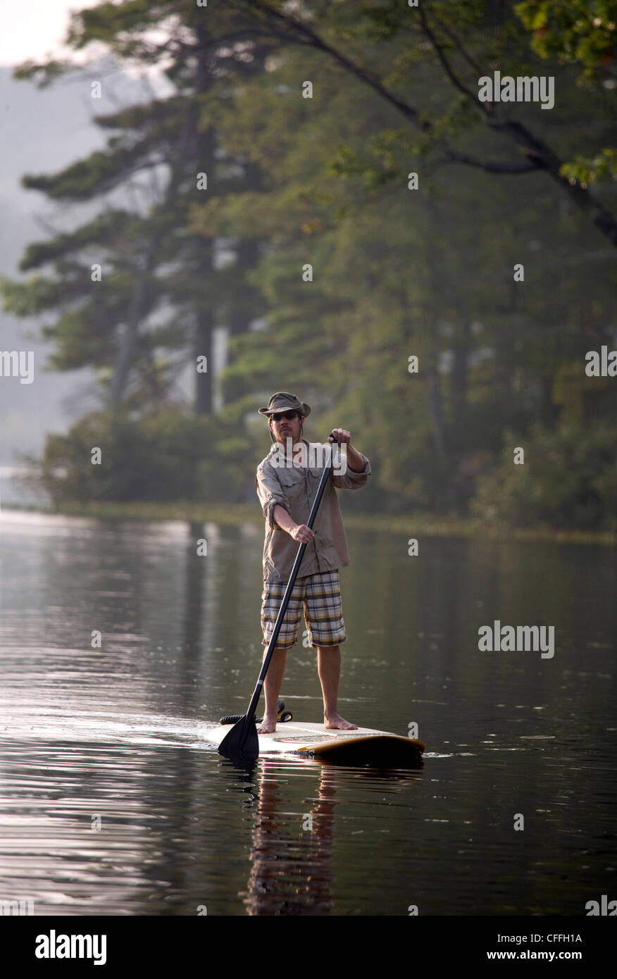 L'uomo cavalca un SUP sul lago Lontra a Greenfield, NH Foto Stock