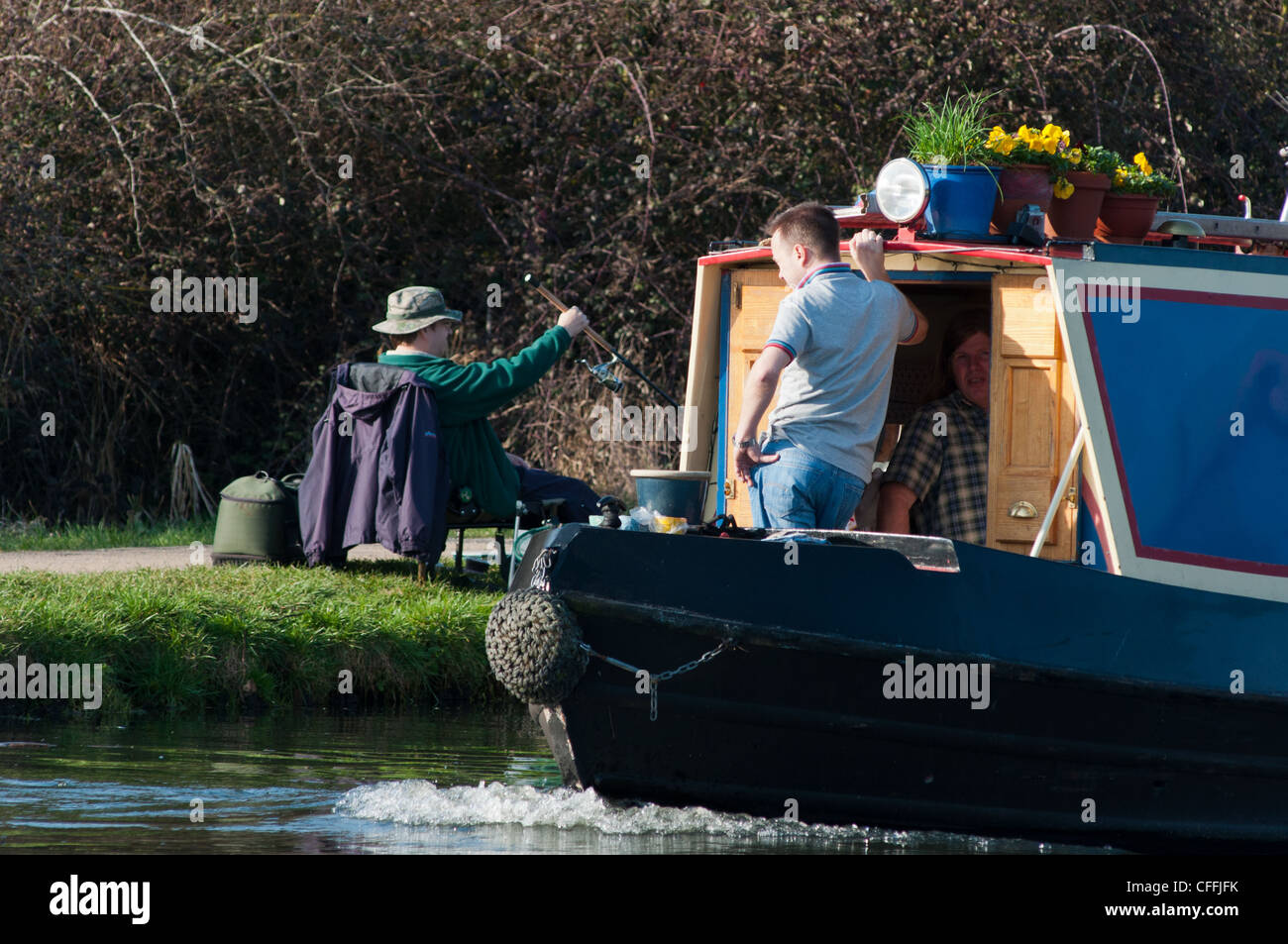 Un uomo pesca come una barca va passato sul fiume Cam. Cambridgeshire, Inghilterra. Foto Stock