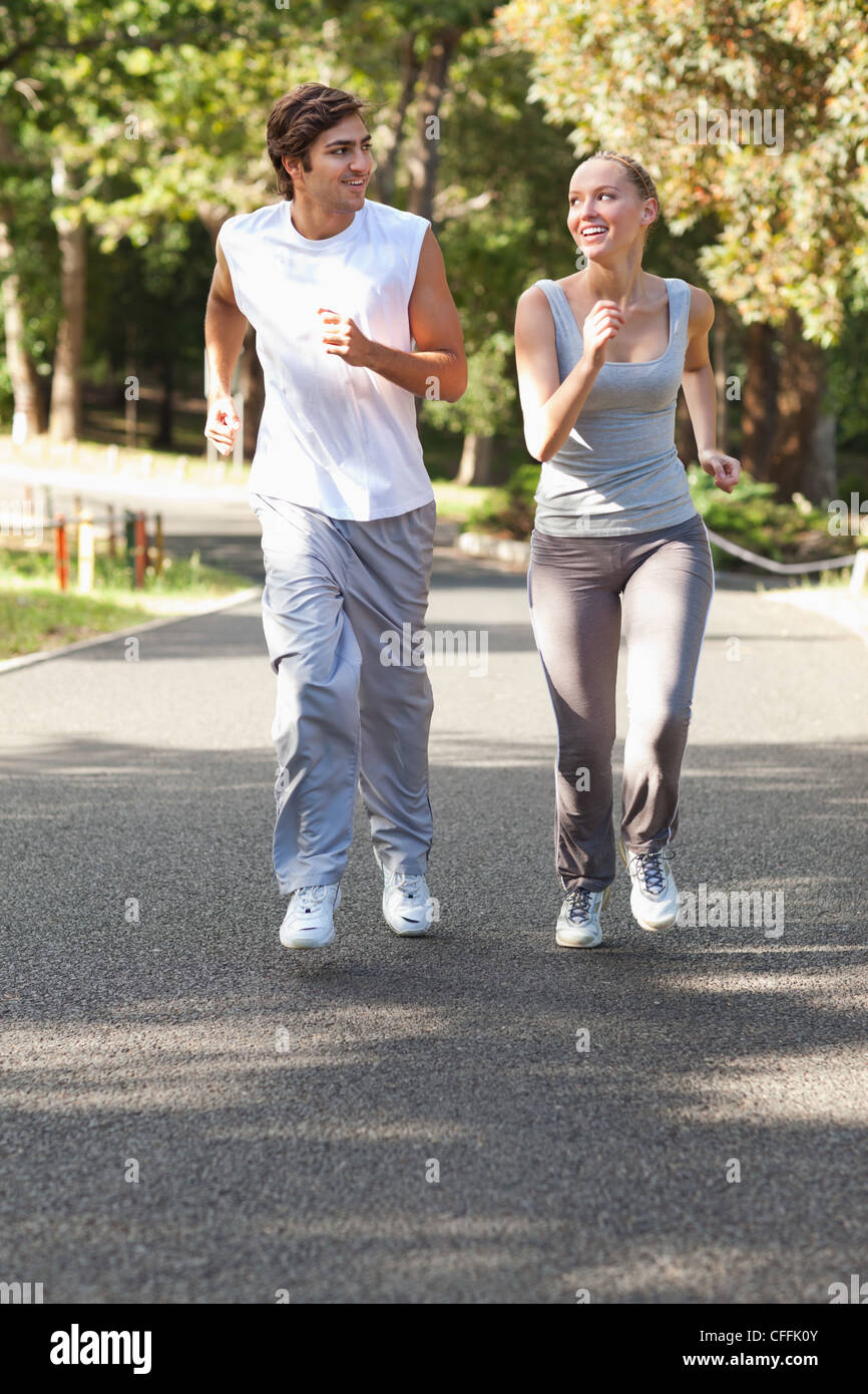 Sorridente team sportivi jogging su un viale Foto Stock