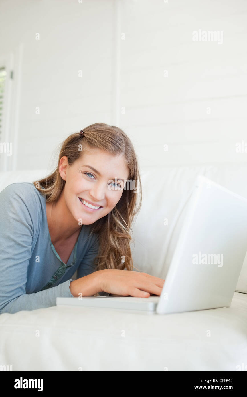 In prossimità di una donna con il suo computer portatile come lei giace sul lettino Foto Stock