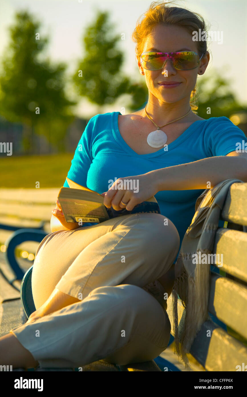 Donna Lettura su una panchina nel parco, Toronto, Ontario Foto Stock