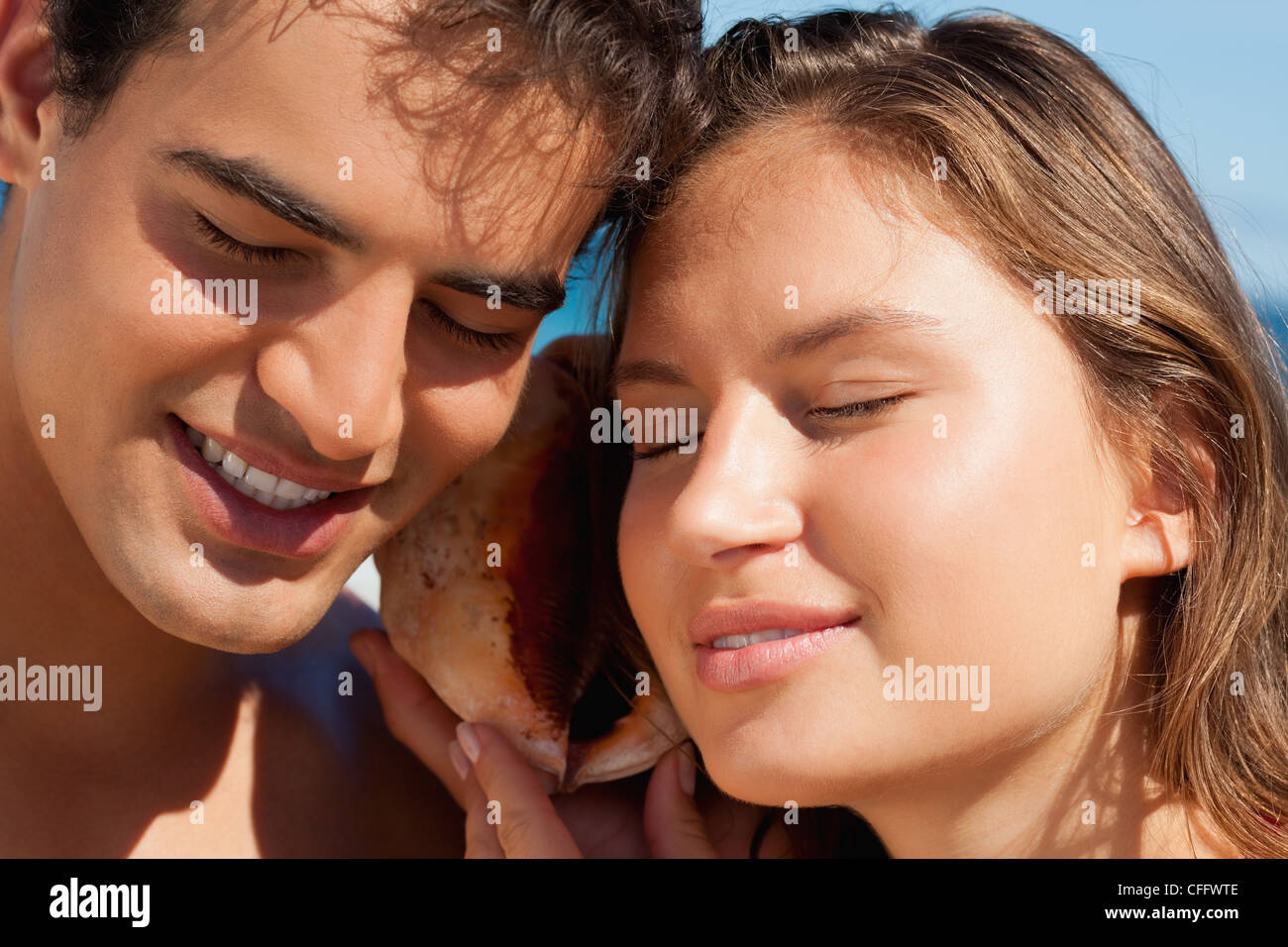 Coppia giovane ascoltando il suono di acqua attraverso una conchiglia Foto Stock