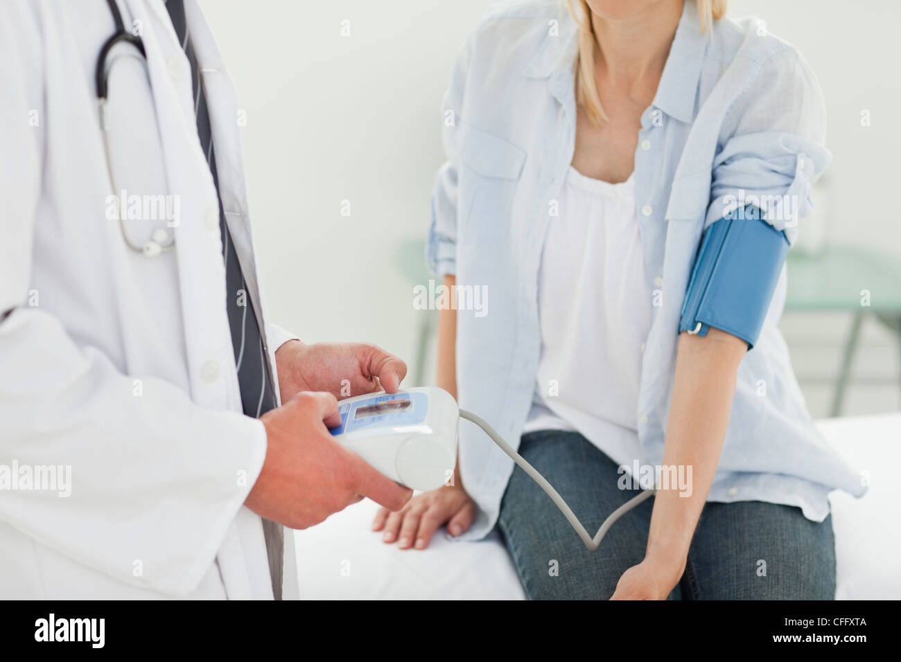 Medico misurare i suoi pazienti la pressione sanguigna Foto Stock