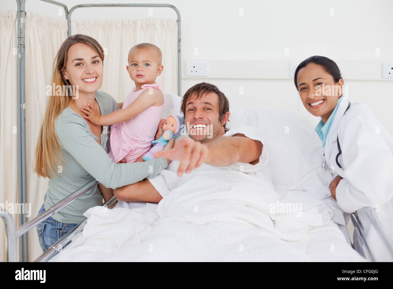 Uomo sorridente puntando la fotocamera mentre è accompagnato dalla sua famiglia Foto Stock