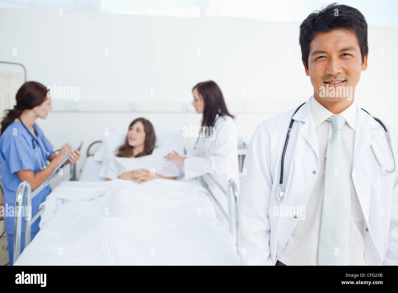 Medico guardando avanti mentre i suoi colleghi il trattamento di un paziente Foto Stock