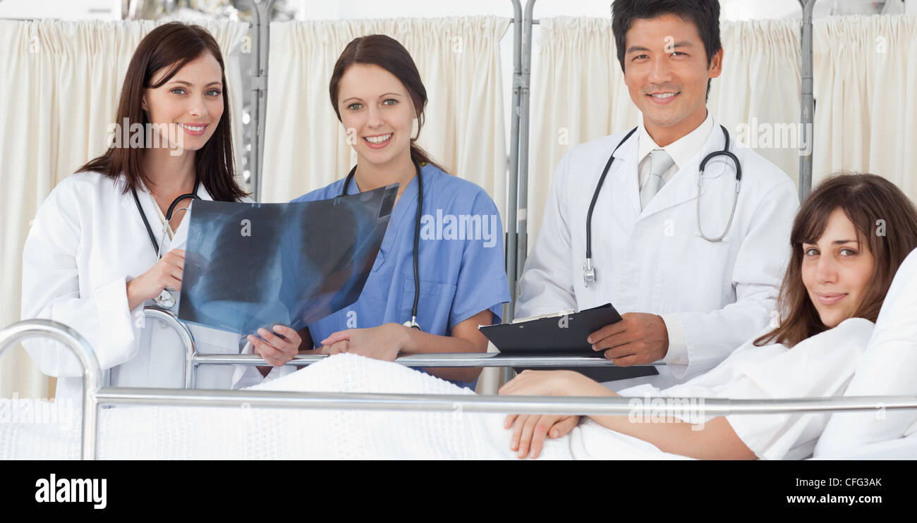Il personale medico alla ricerca di una scansione a raggi x mentre in piedi accanto ad un paziente Foto Stock